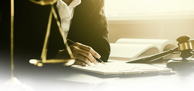 Person writing notes with an open book and gavel closeby